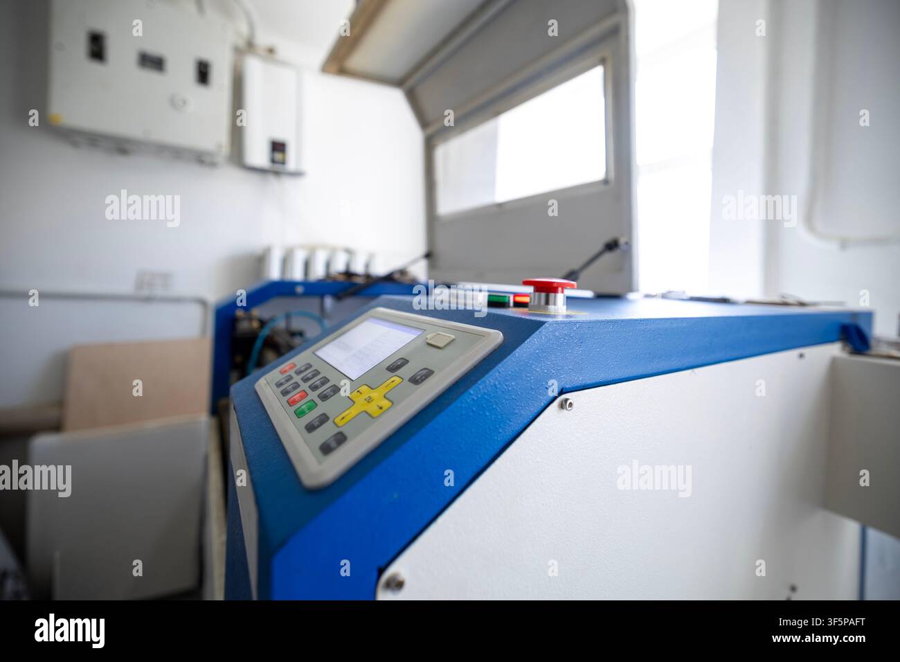 Industrial cnc laser cutting machine with control panel interface and safety emergency stop button in a bright workshop space electrical boxes mounted Stock Photo