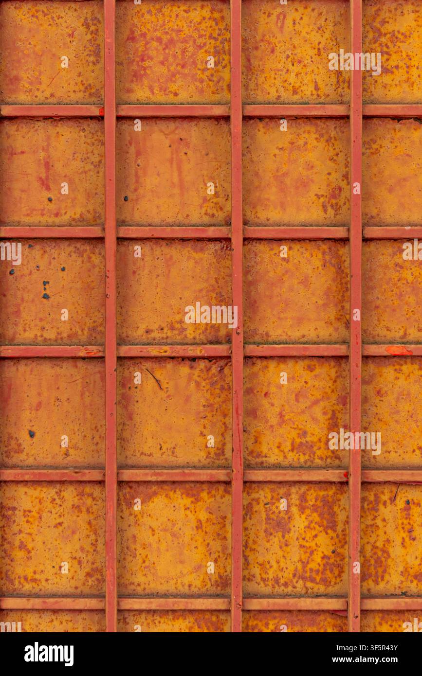 Rusty yellow metal grid panel background with red painted frame lines and heavy oxidation texture Stock Photo
