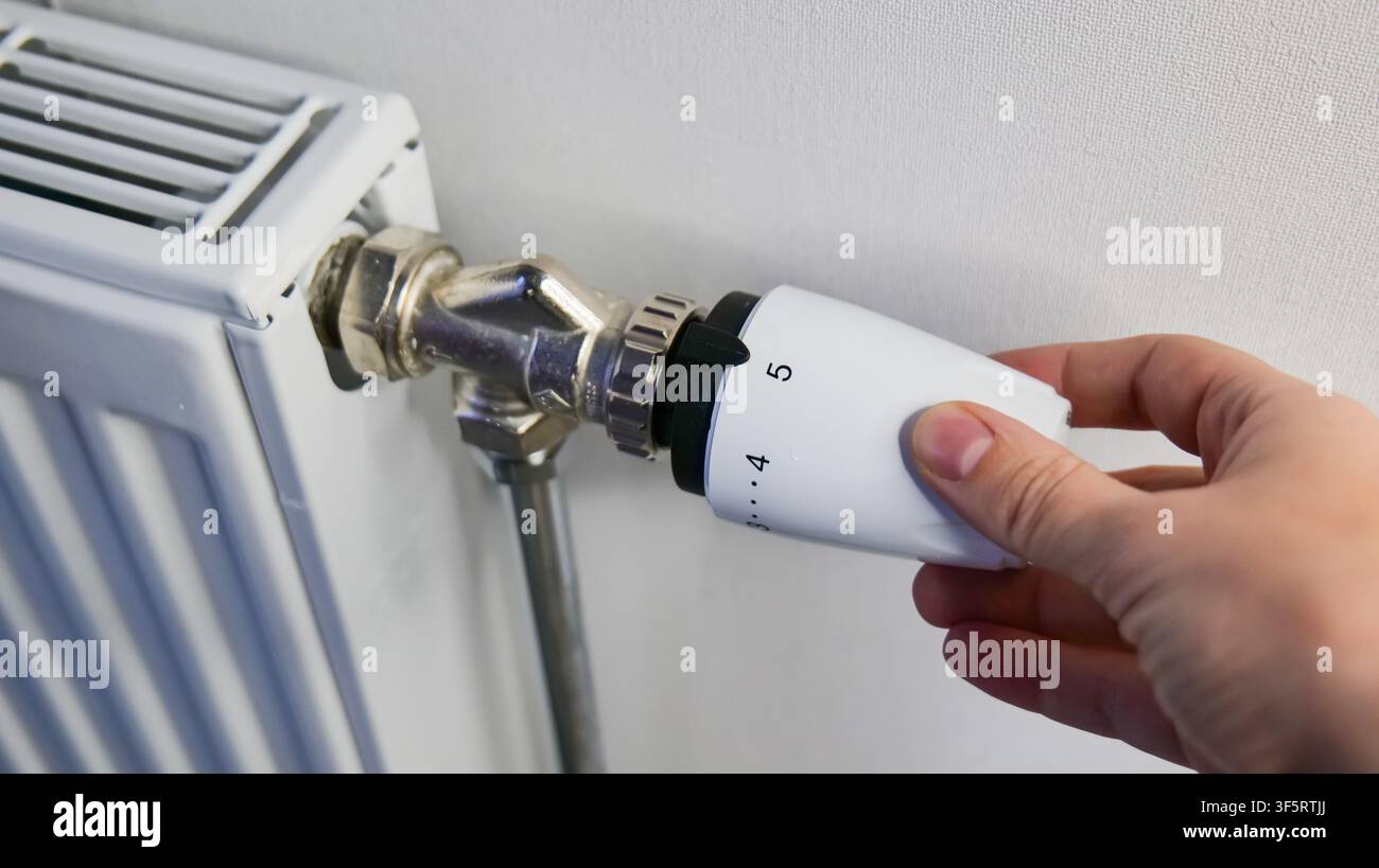 Hand Adjusting Temperature on Wall Mounted Heating Radiator Stock Photo