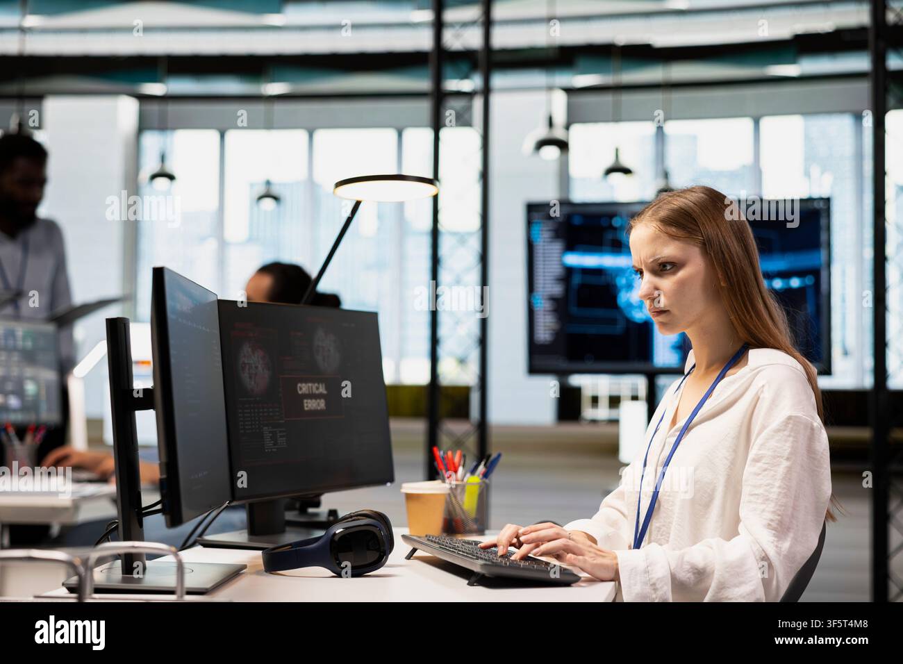 Female engineer in startup office struggling to fix application errors while coding. Young IT professional dealing with computer bugs while coding in software development agency Stock Photo