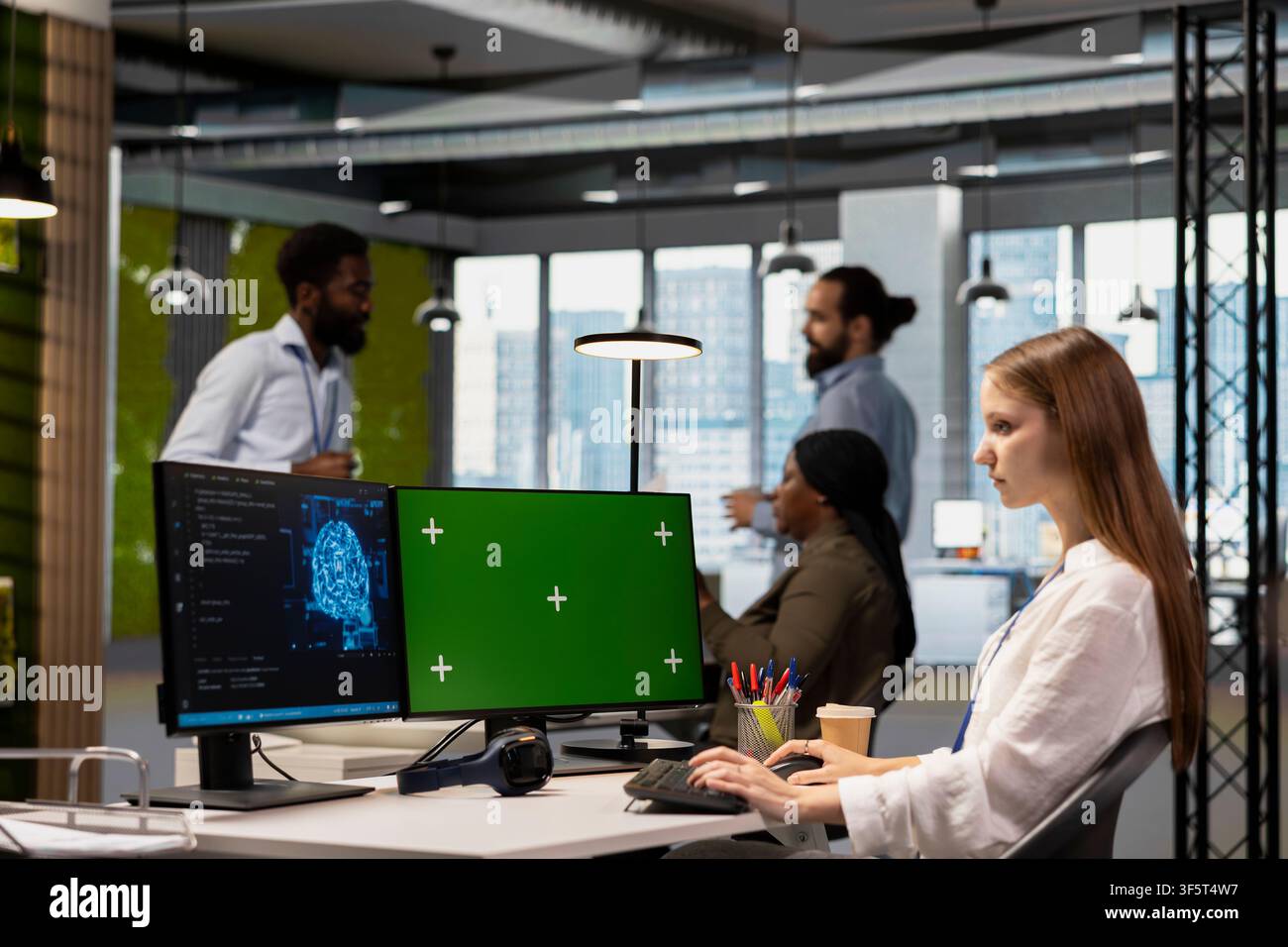 Junior developer using mockup PC, writing code, developing machine learning APIs. Young technician in office troubleshooting software errors using artificial intelligence tech on green screen computer Stock Photo