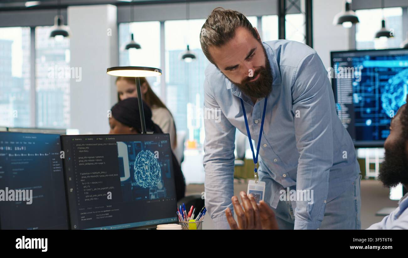 Manager supervising developer with paraplegia writing code, developing deep learning APIs. Supervisor overseeing work done by IT expert in wheelchair troubleshooting software errors using AI, camera A Stock Photo