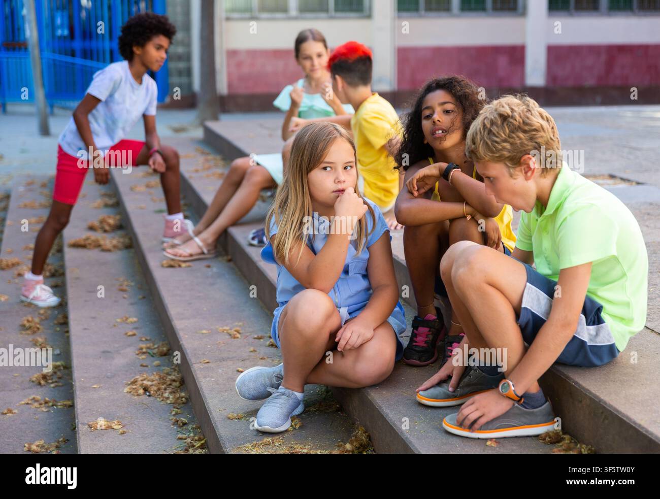 Positive tweenagers friendly blabbing while sitting on steps outdoors Stock Photo