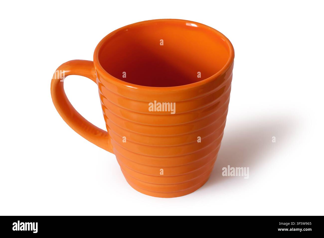 Empty ceramic cup on a white background. Orange cup close-up with shadow Stock Photo