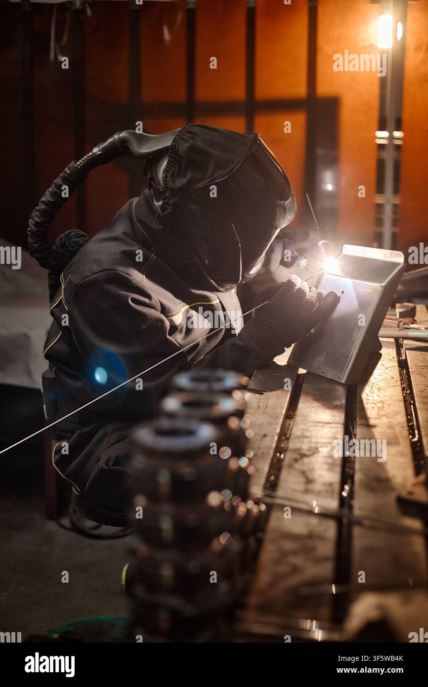 Professional Welder in Protective Gear Working on Metal in Workshop Stock Photo