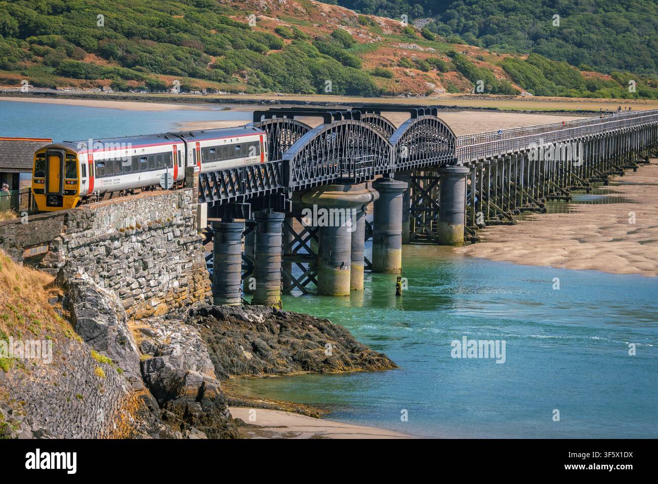 A Trains for Wales DMU passes over the Barmouth viaduct on the Mawddach estuary crossing the river Mawddach. Stock Photo