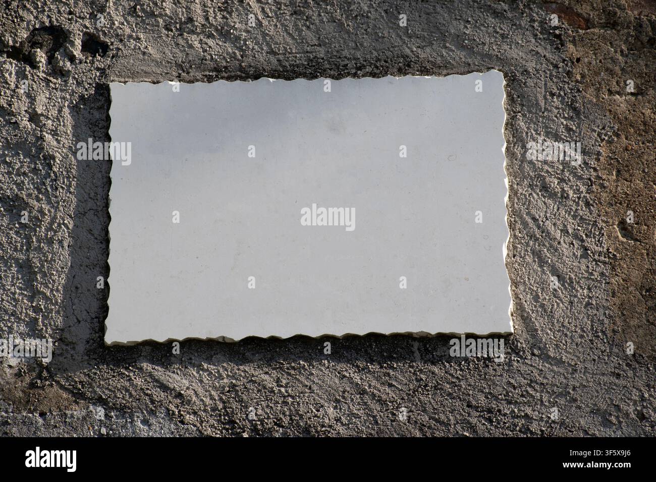 empty marble plaque hanging on the concrete wall Stock Photo