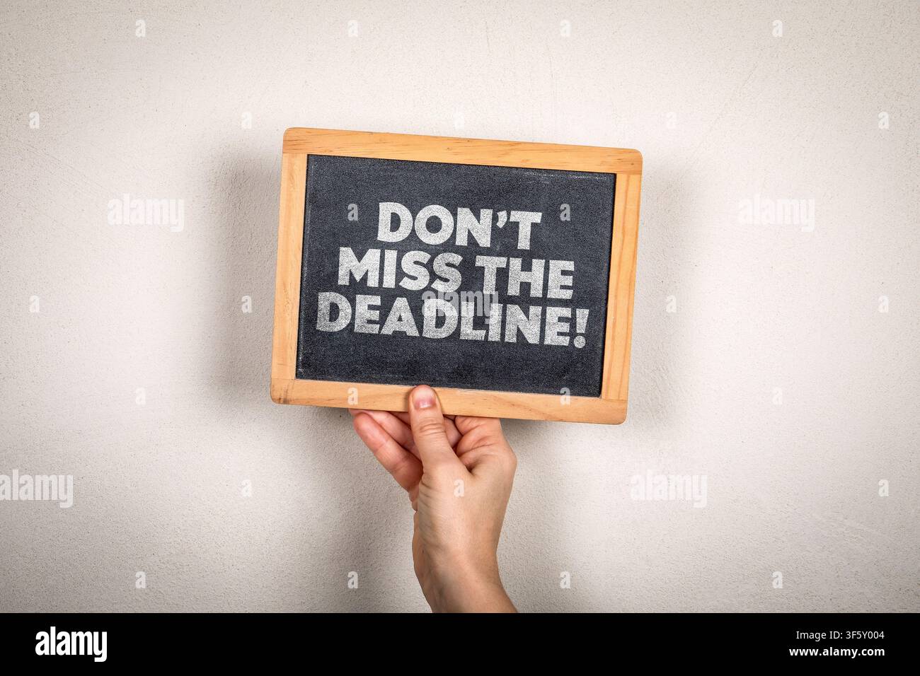 DONT MISS THE DEADLINE! warning concept displayed on handheld blackboard with copy space Stock Photo