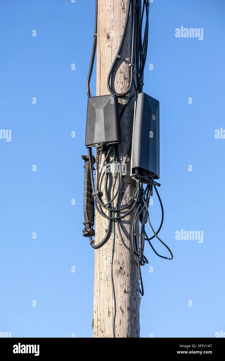 Communication Network Devices Installed on Utility Pole Against Clear Blue Sky Background Stock Photo