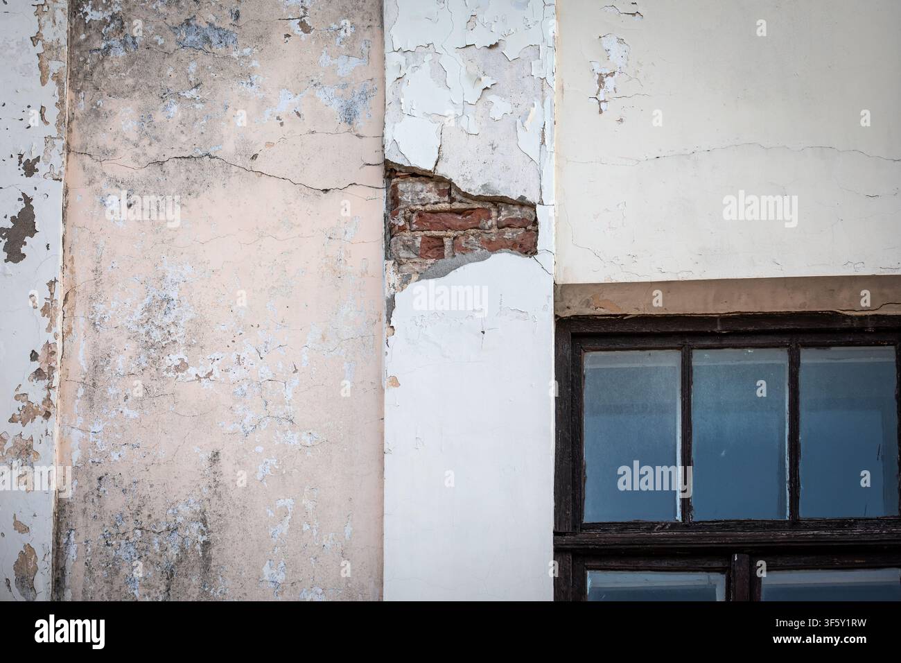 Old Wall Surface With Peeling Paint Cracks and Visible Brick Under Plaster Stock Photo