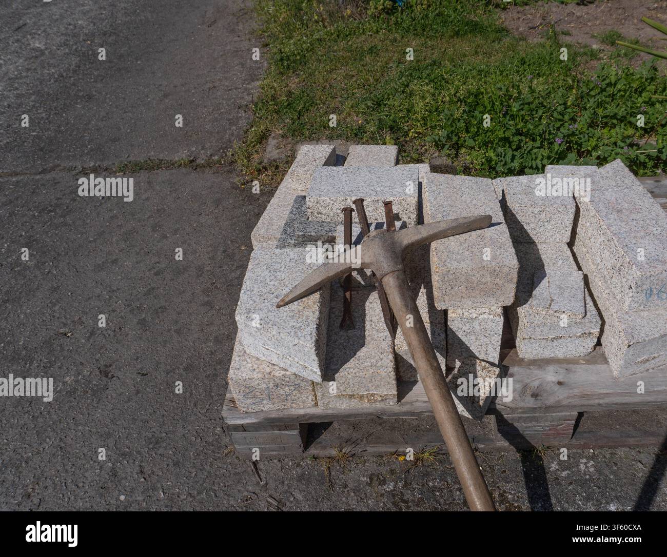 Weathered pickaxe resting on stacked granite blocks  Stock Photo