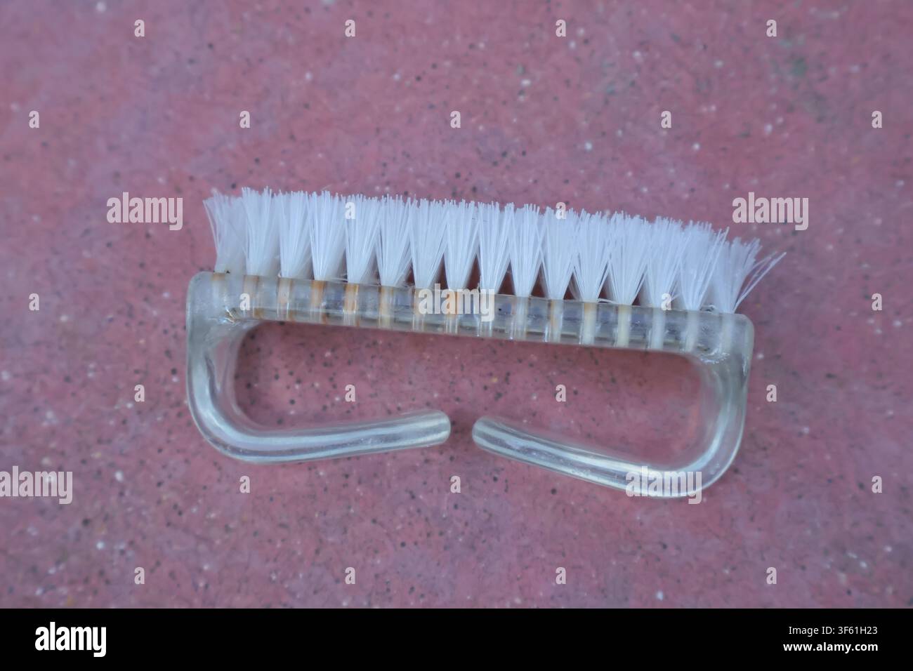 Small white cleaning brush with plastic handle on pink background. Stock Photo