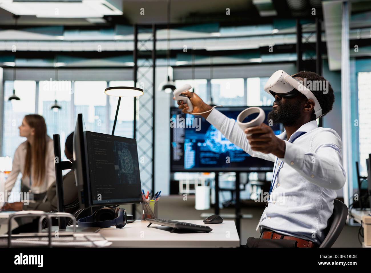 Developer wearing VR goggles at office desk developing programs using AI automation. Tech company worker using virtual reality equipment, debugging applications with artificial intelligence Stock Photo