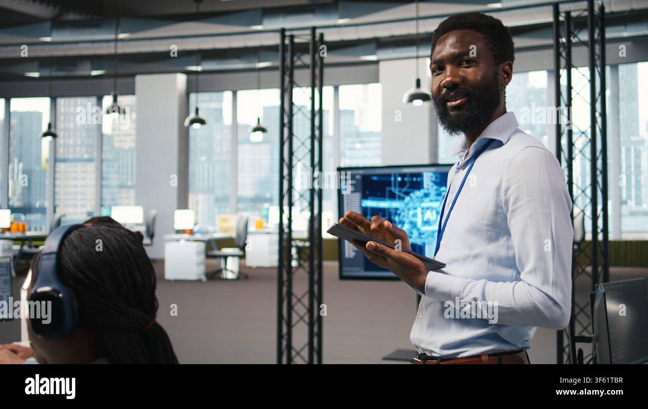 Joyous technician in office automating repetitive tasks using AI scripts. Upbeat man in workplace using artificial intelligence to speed up feature implementation, camera A Stock Photo