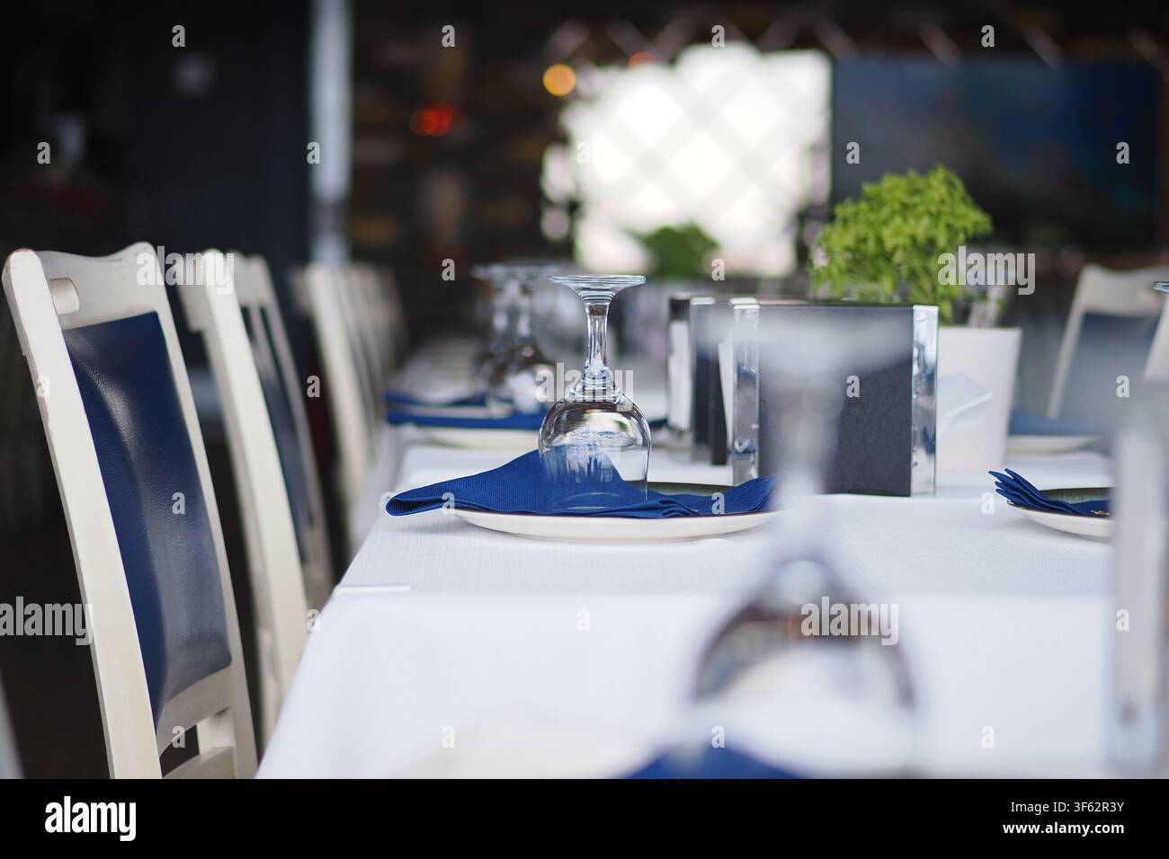 Table set for dinner at a restaurant with blue napkins Stock Photo