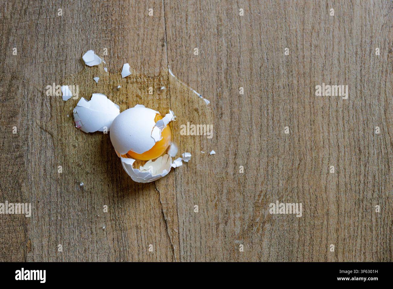 Broken Raw Egg with Cracked White Shell on a Rustic Wooden Table Surface Stock Photo