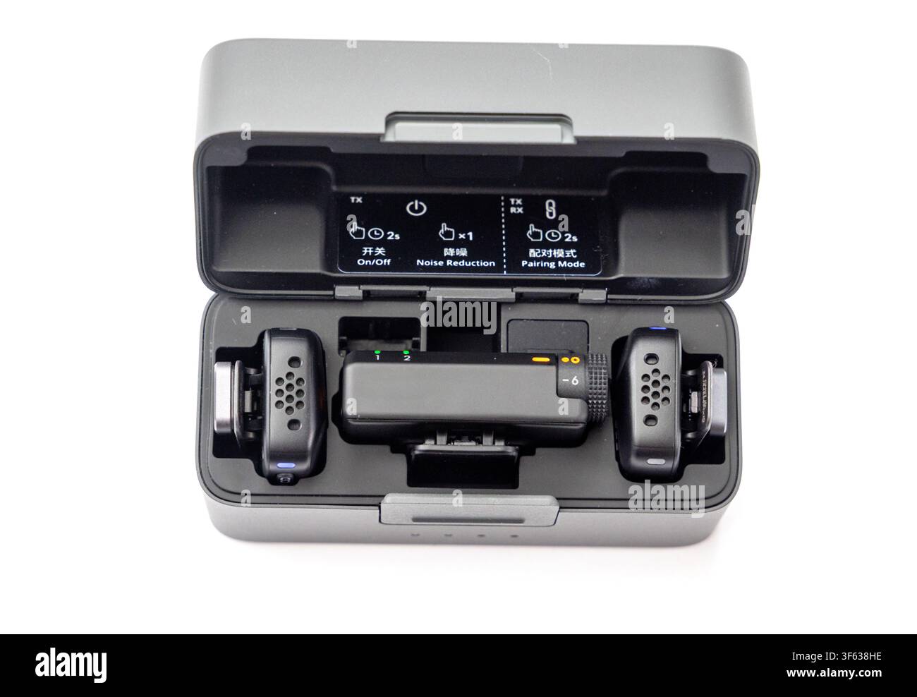 A wireless microphone set including transmitters and receiver sits neatly inside its open charging case against a plain white background Stock Photo