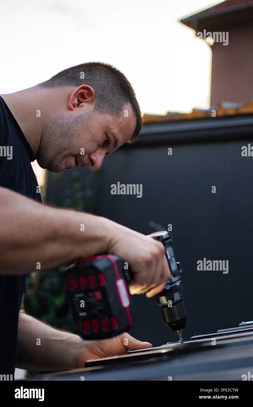 Man using power drill for construction work outdoors Stock Photo