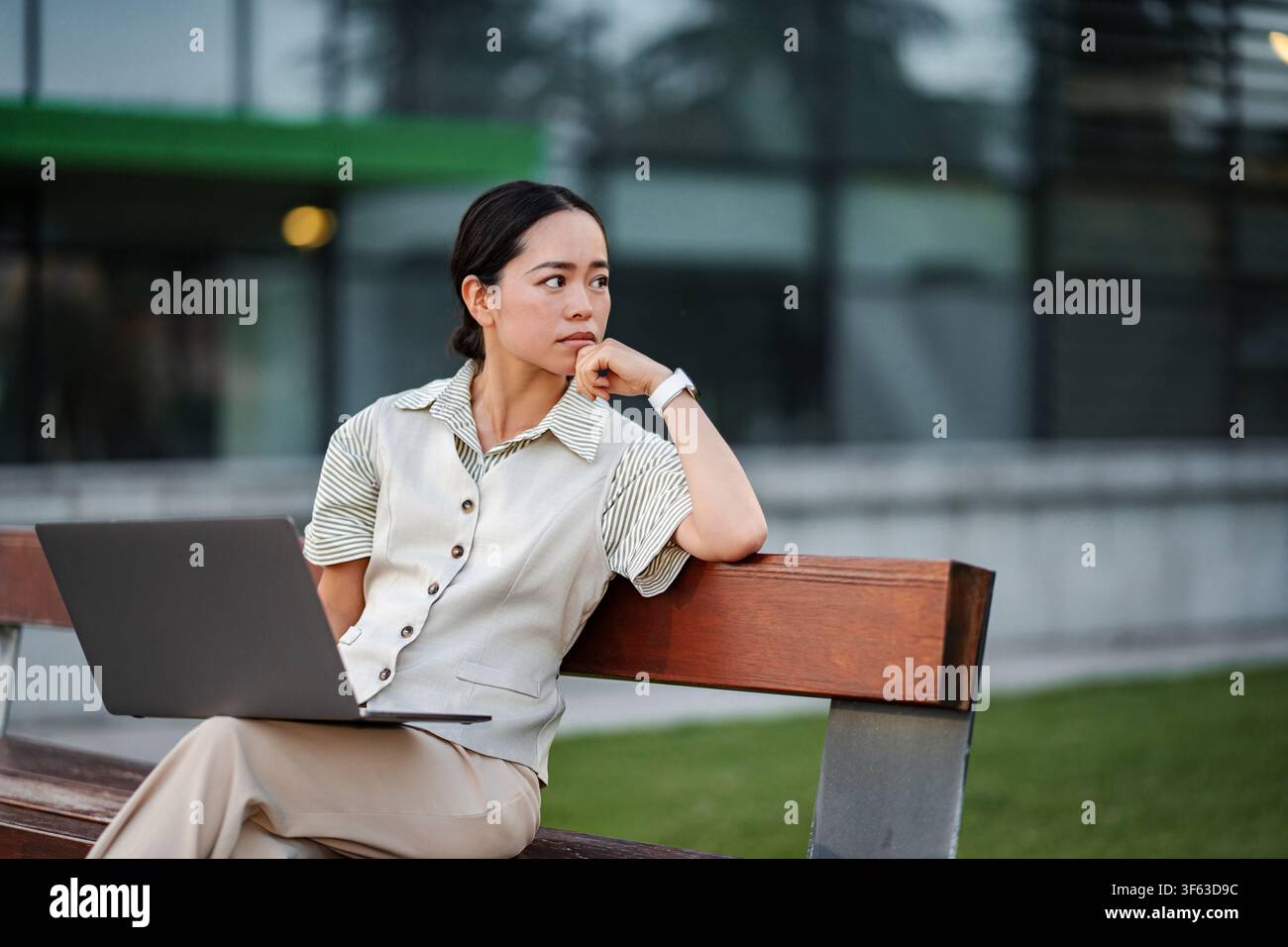 Asian businesswoman contemplating work project outdoors on bench Stock Photo