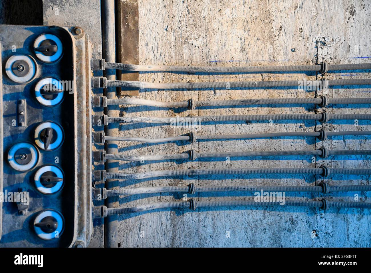 Old surface-mounted electrical wiring with rotary switches in an industrial facility Stock Photo
