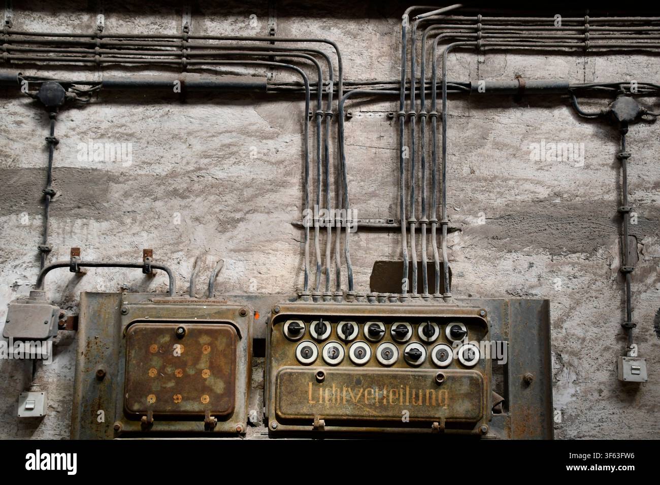 Old surface-mounted electrical wiring with rotary switches in an industrial facility Stock Photo
