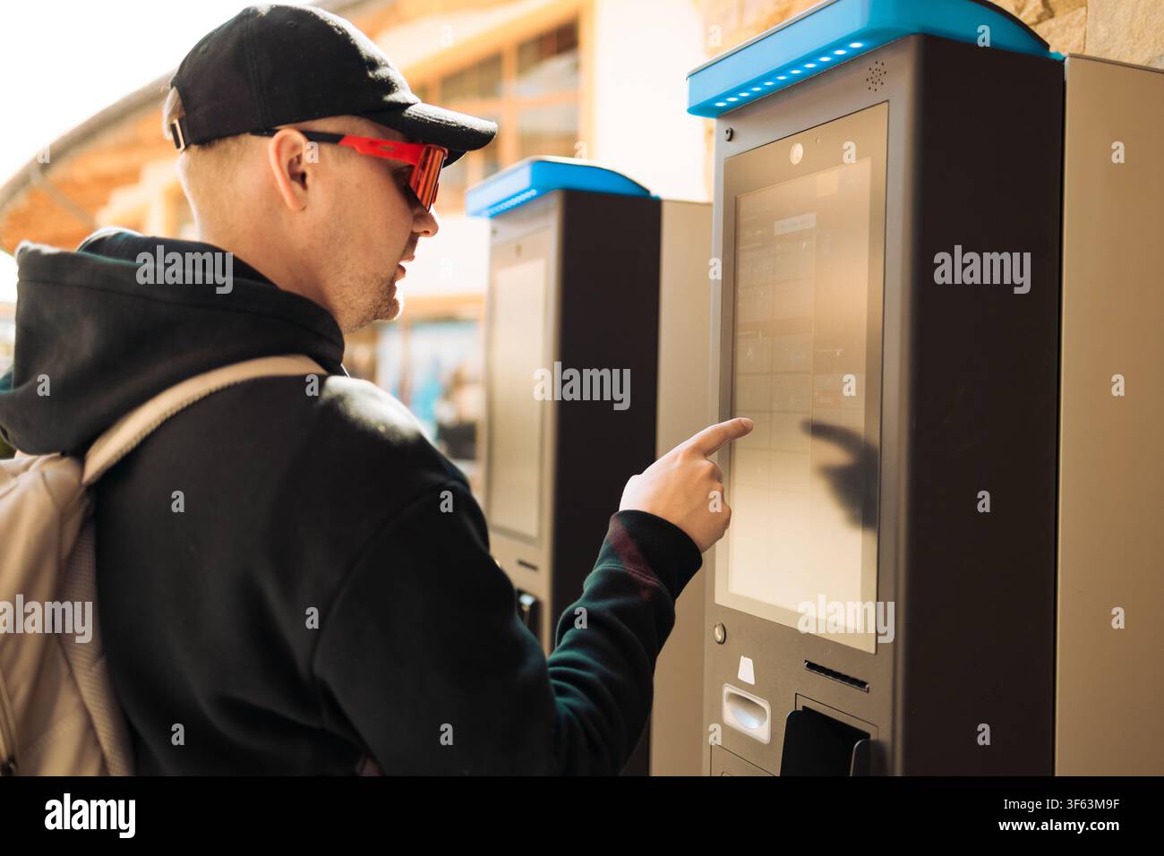 Young man using outdoor automated ticket machine or parking meter Stock Photo
