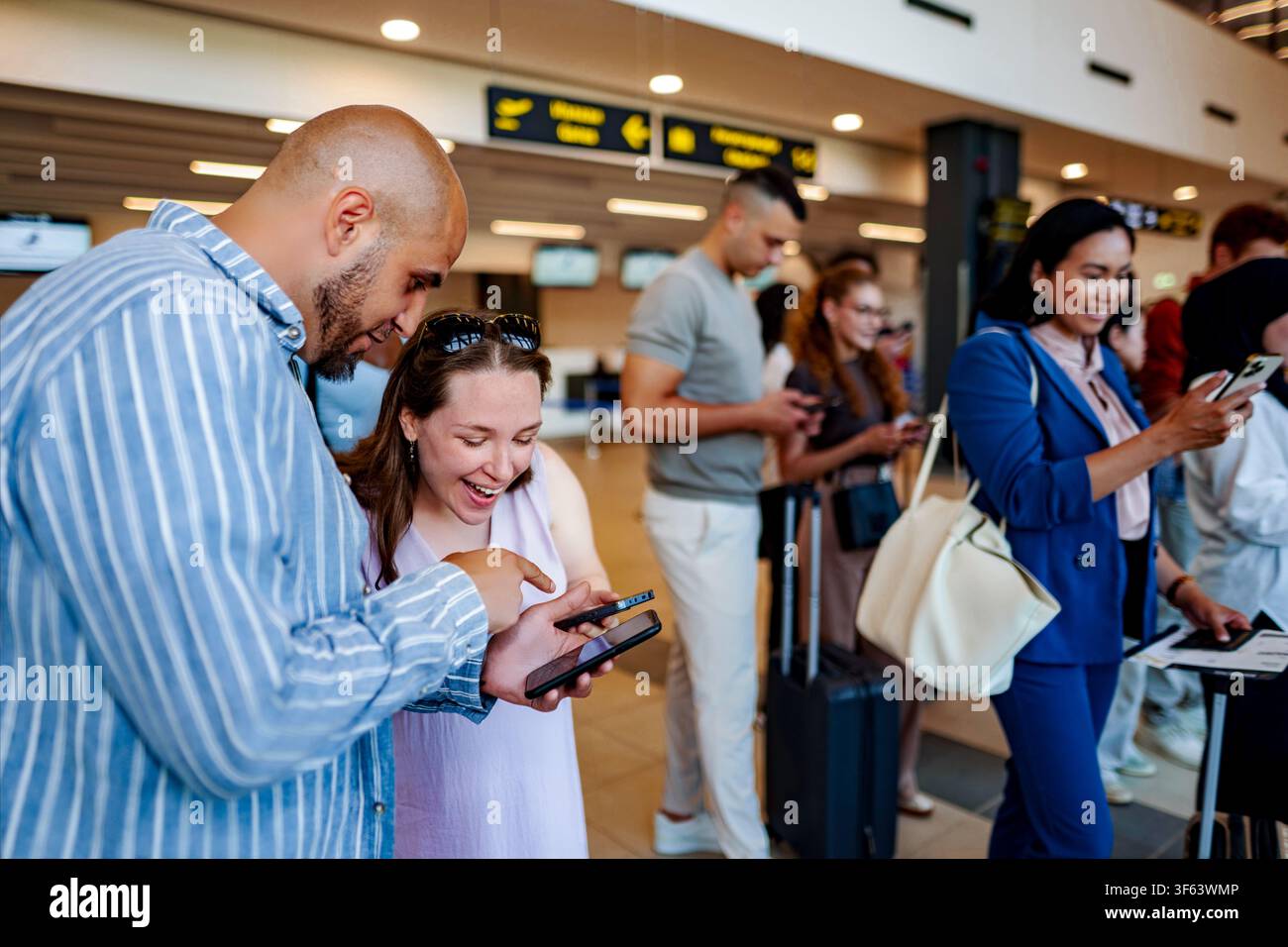 People using smartphones waiting in airport queue Stock Photo