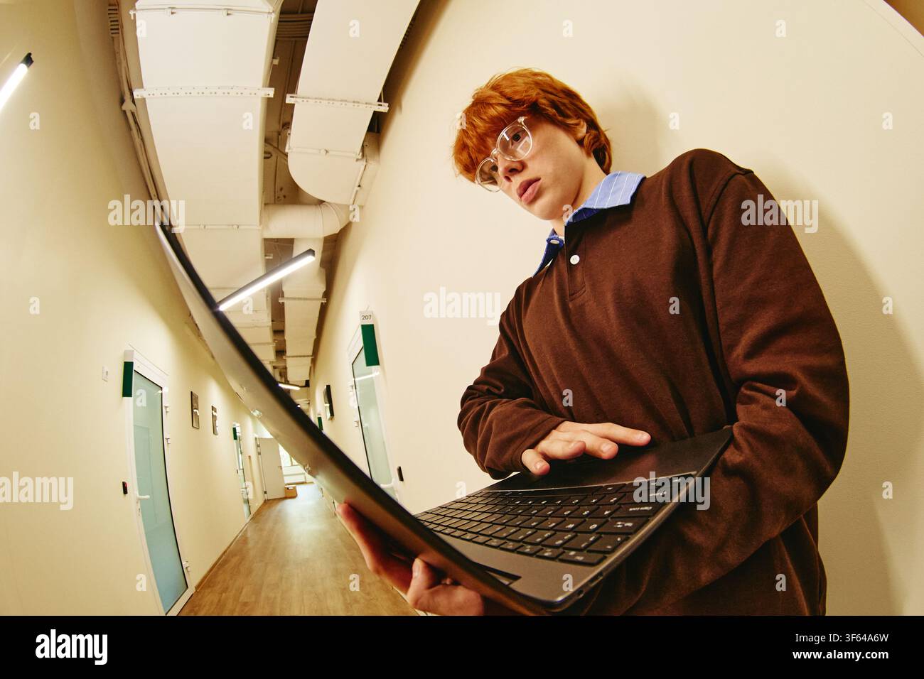 Man Using Laptop in Office Corridor for Digital Learning Stock Photo