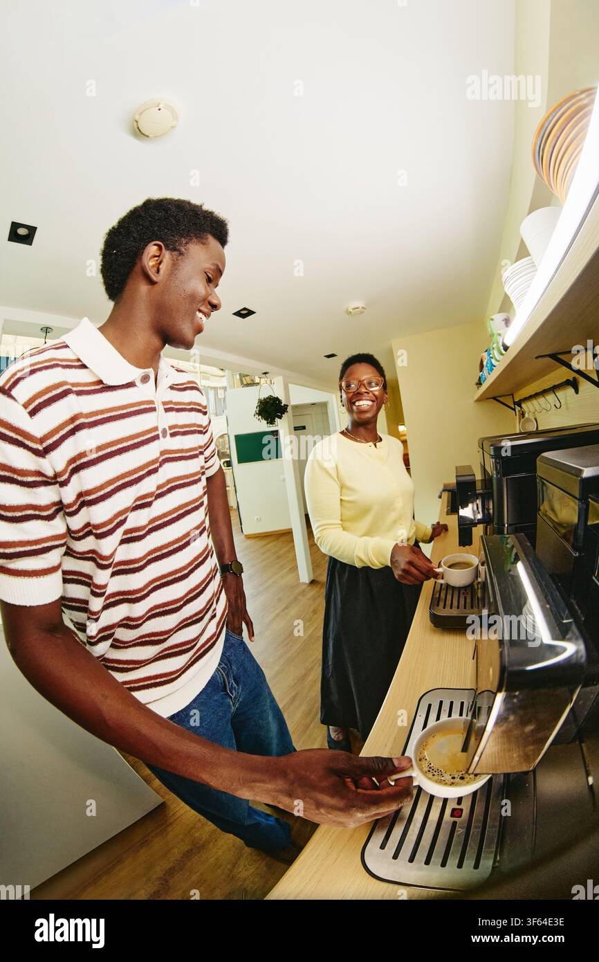 Black Colleagues Making Coffee in Office Kitchen during Break Stock Photo