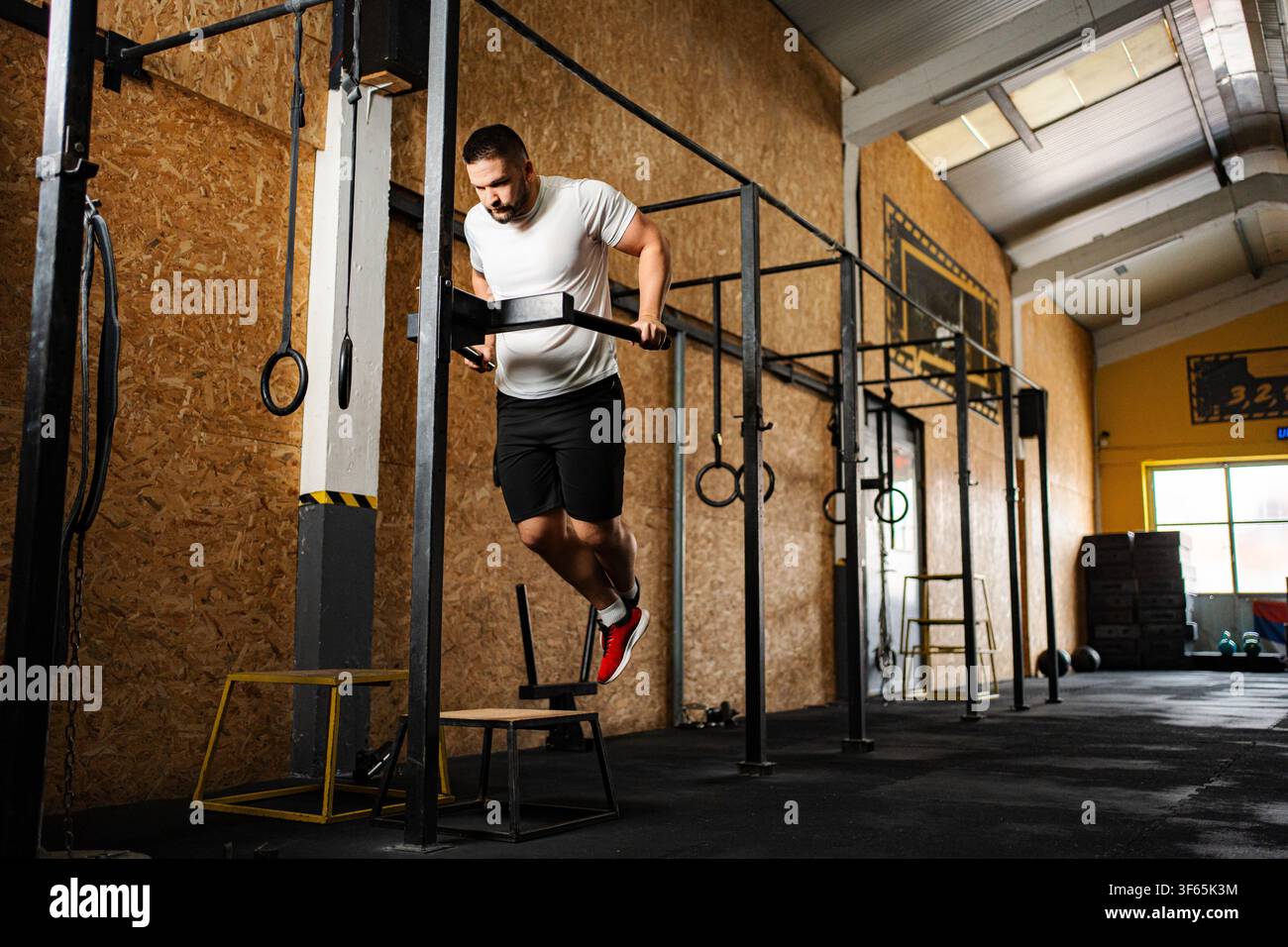Athletic man doing dips at crossfit gym Stock Photo