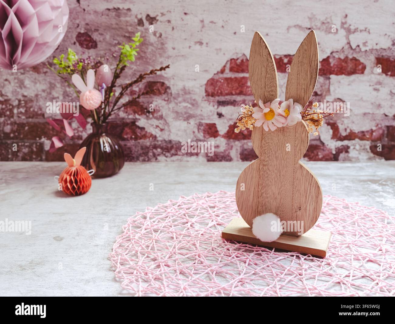 Decorative Easter bunny displayed beside a ceramic vase and festive Easter decorations on a rustic background Stock Photo