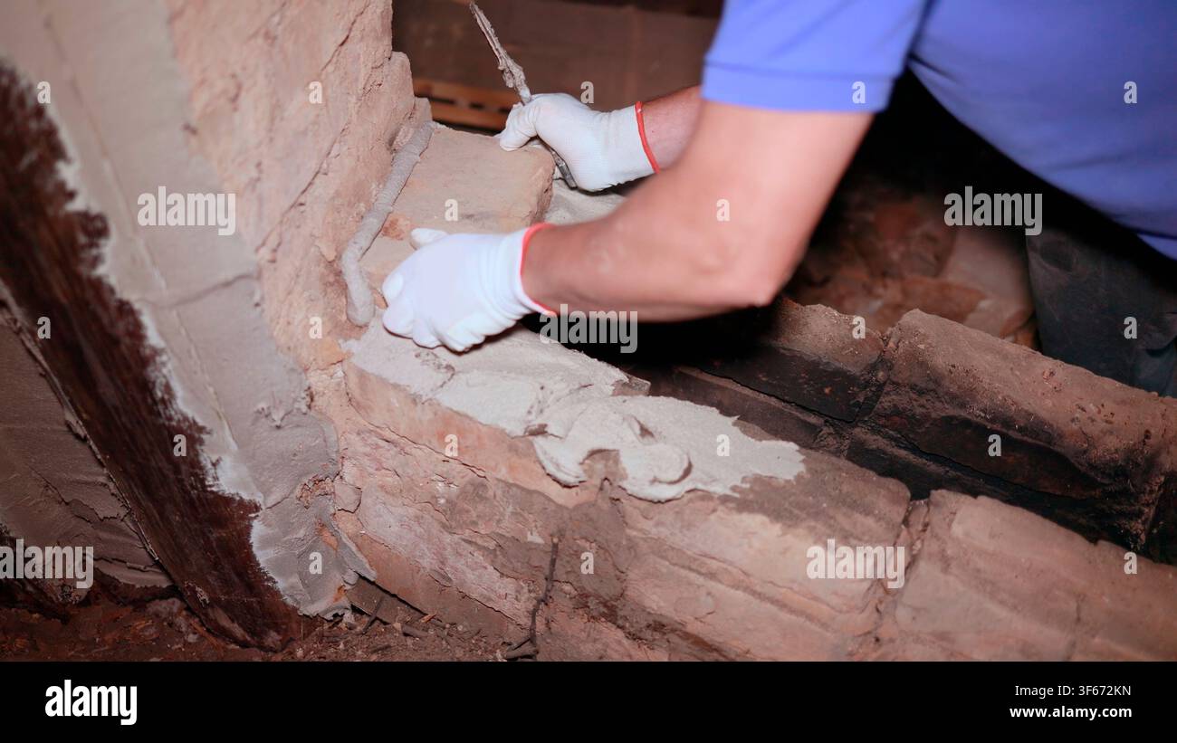 Construction worker restoring an old brick wall using mortar and trowel Stock Photo