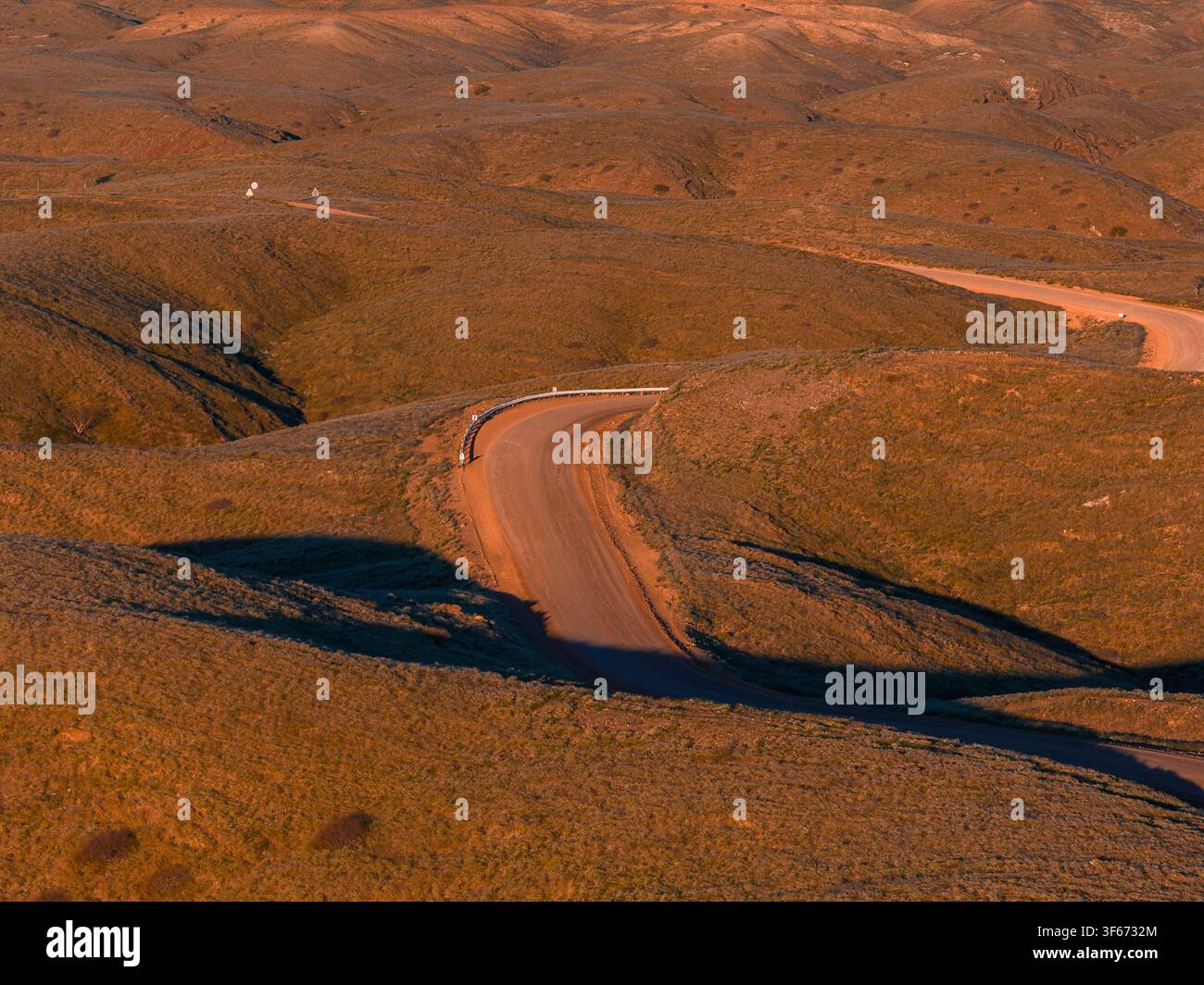 Aerial view of winding dirt road through ochre hills in Namibia at sunset Stock Photo