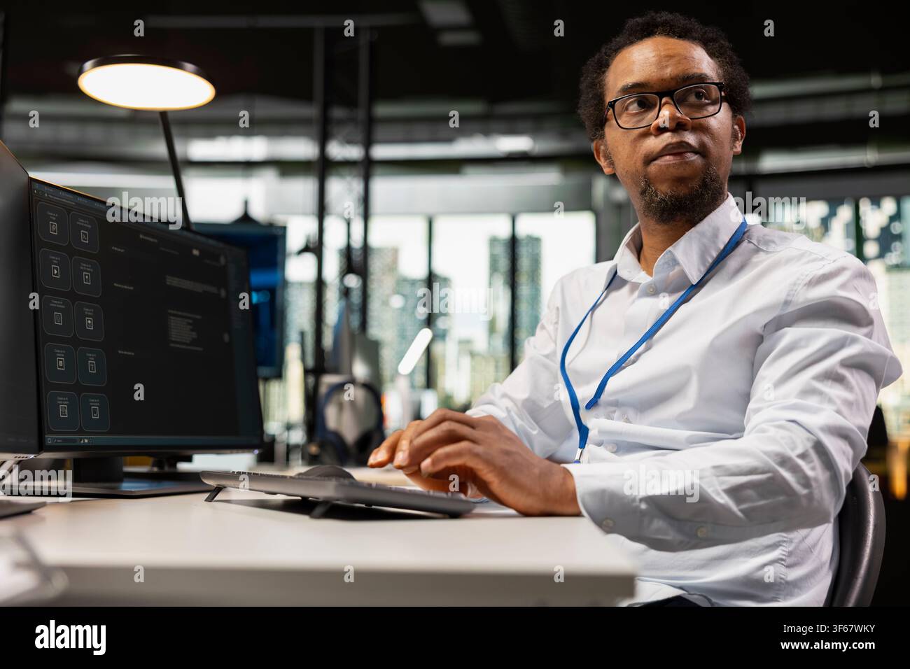 System administrator solving tasks with AI LLM chatbot answering prompts using predictive technology. African american man using computer to interact with large language model program Stock Photo