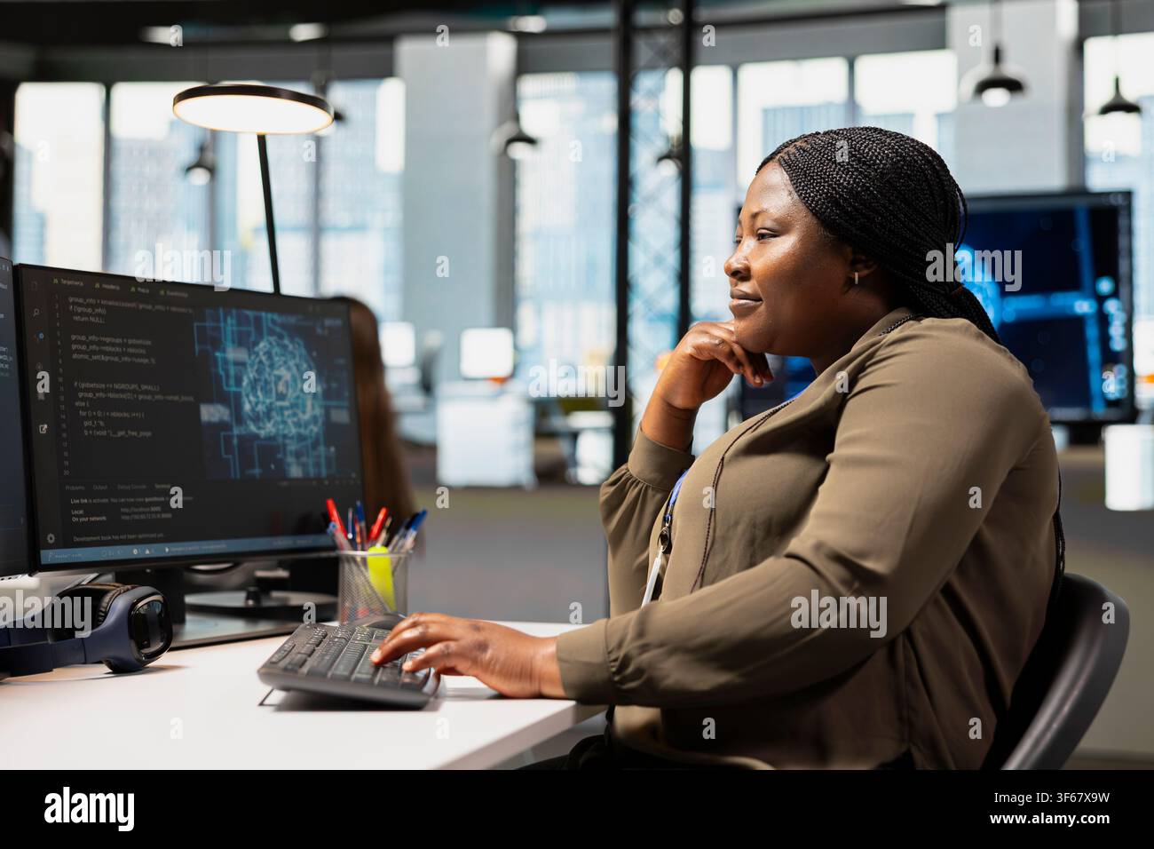 Joyful IT employee in tech startup uses AI on PC to optimize performance and forecast issues. Happy software developer in office training machine learning models using computer Stock Photo