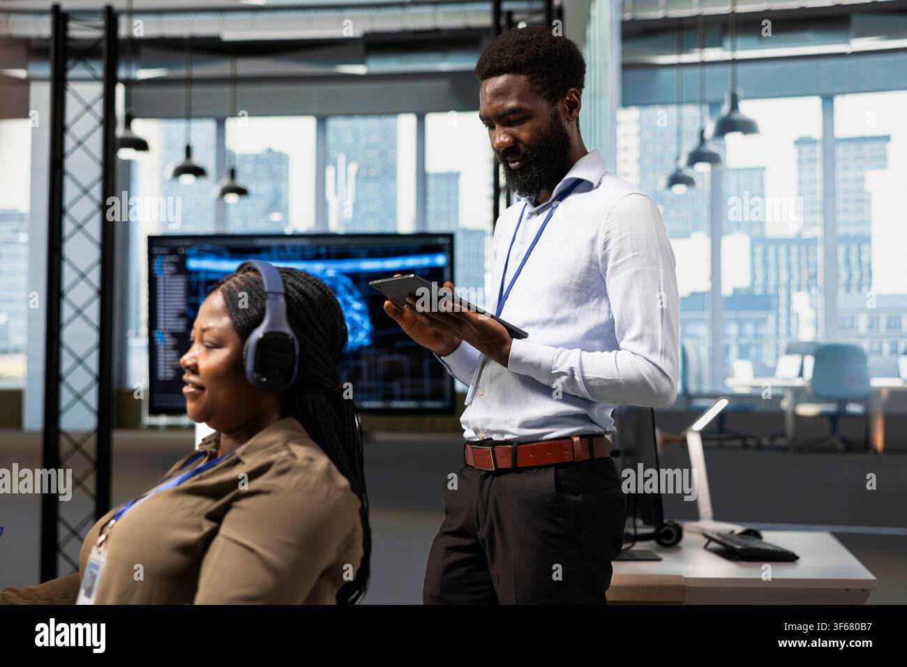Technician developing applications using tablet, integrating AI next to office coworkers. IT specialist debugging applications with device using artificial intelligence in tech startup Stock Photo