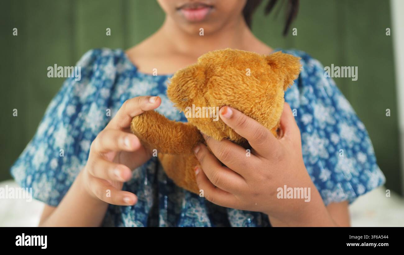 Child holding a teddy bear indoors in a home setting Stock Photo