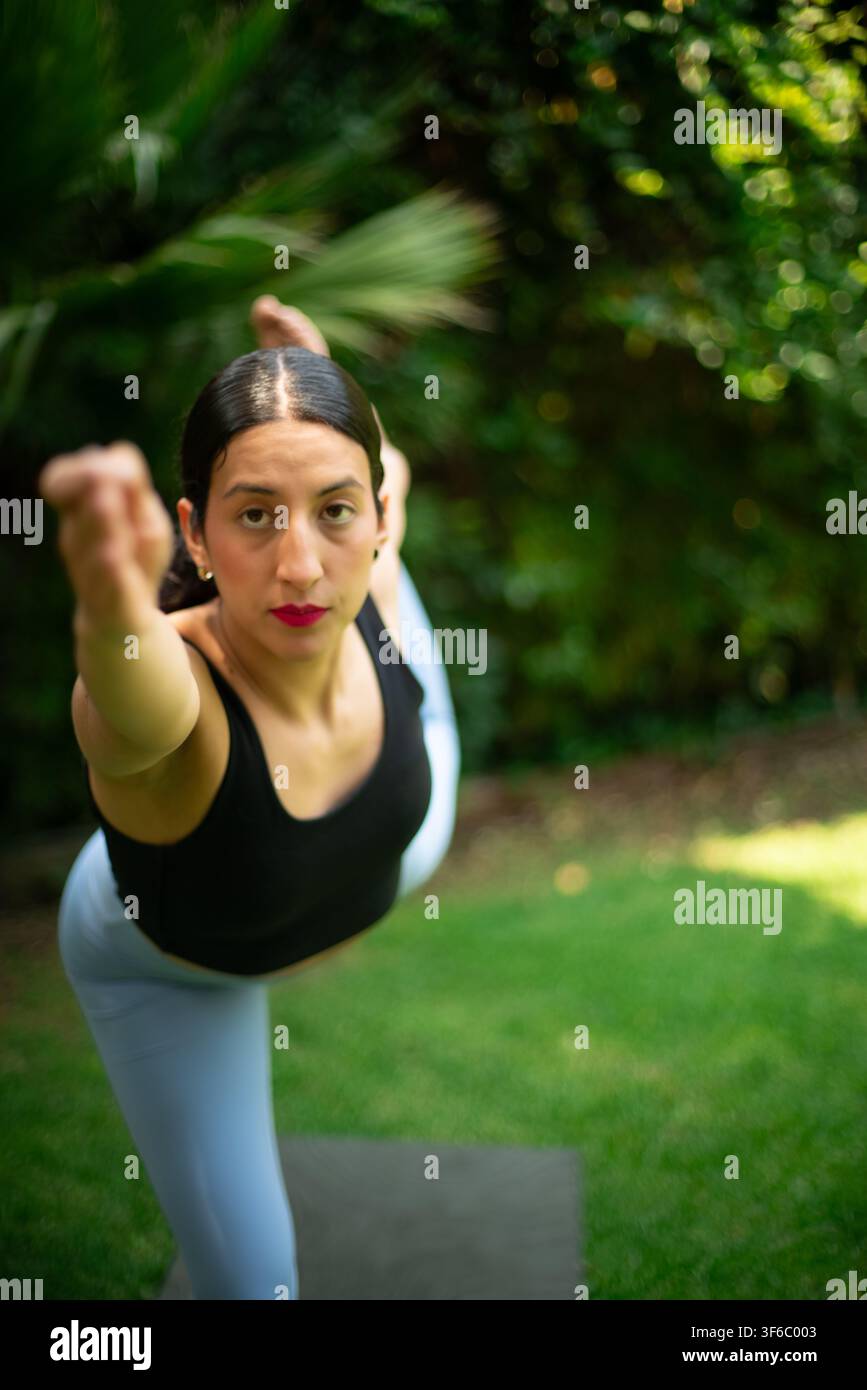 Woman practicing yoga dancer pose in garden Stock Photo