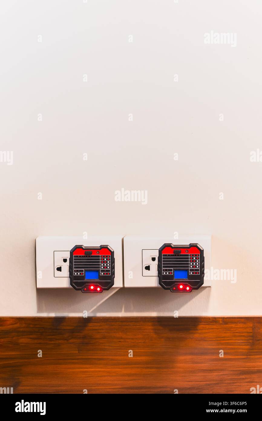 Two digital socket testers plugged into wall outlets to check electrical wiring Stock Photo