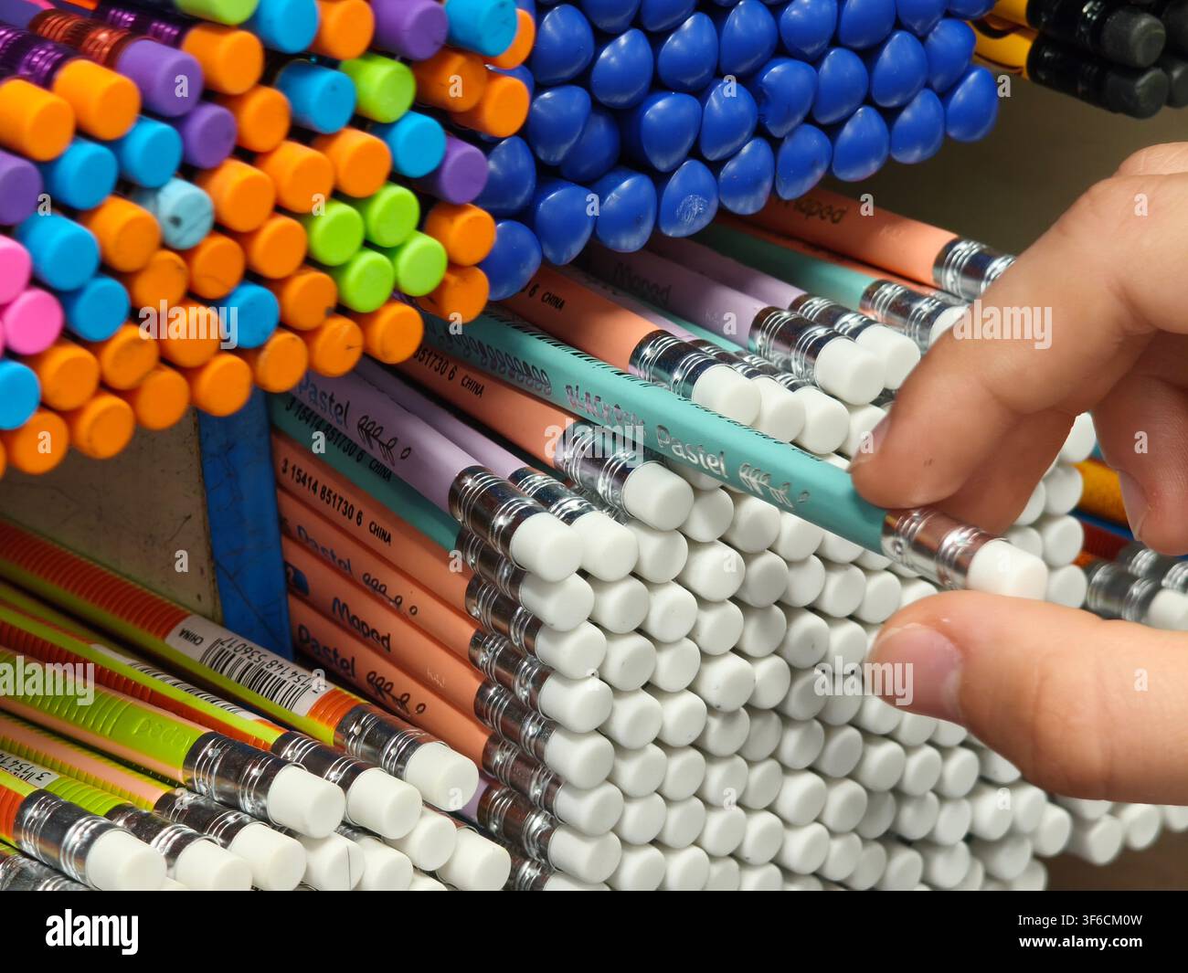 Customer hand choosing a pastel colored pencil from a large store shelf display - Smartphone Captured Stock Image