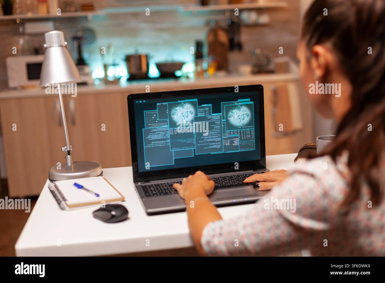 Female programmer works from home on malicious software intended to breach a protected firewall during a late-night cyberattack. Stock Photo