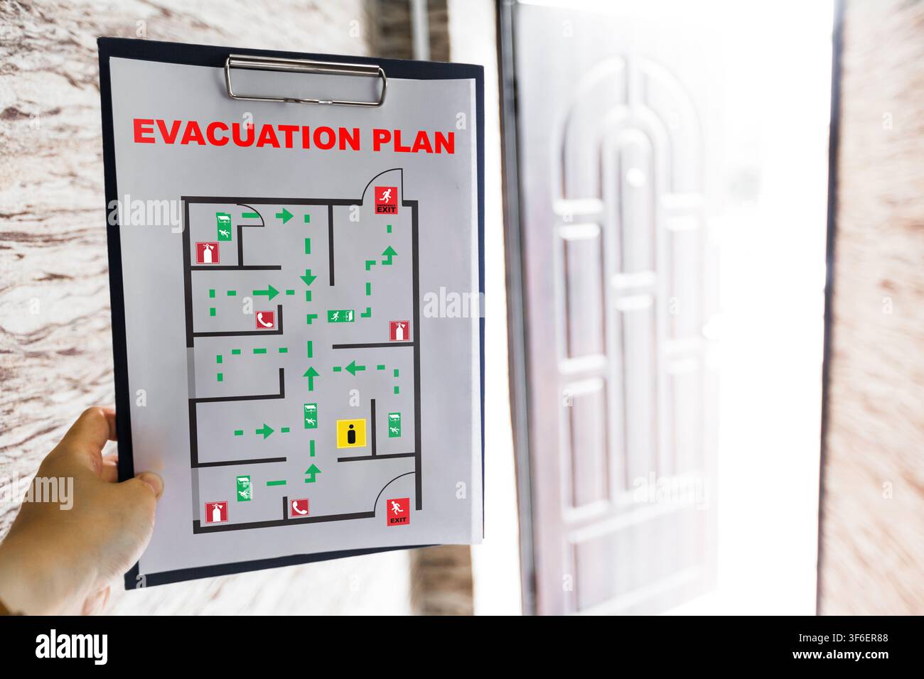 Emergency evacuation plan displayed on wall near exit door Stock Photo