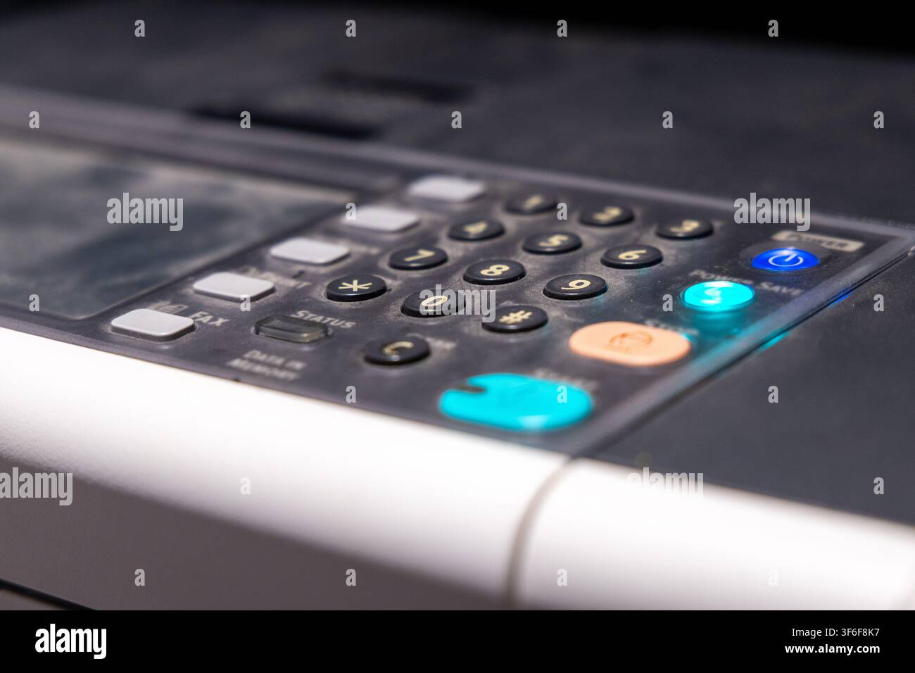 Detailed view of a multi-function device control panel featuring a numeric keypad, function buttons, and glowing indicator lights Stock Photo