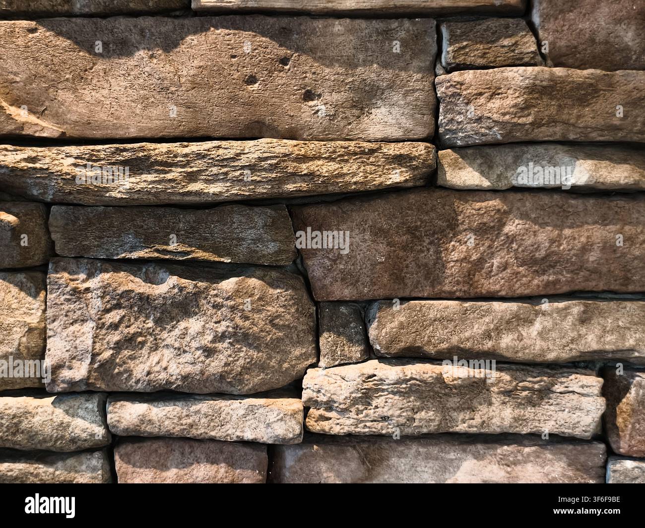 Natural stacked stone wall cladding texture with rough surface background Stock Photo