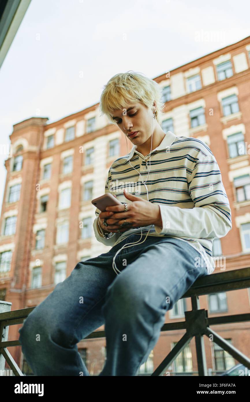 Man Using Smartphone and Earphones Outdoors Stock Photo