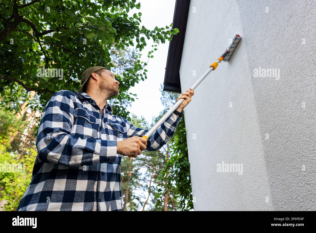 house painter restore paint on building exterior with roller Stock Photo