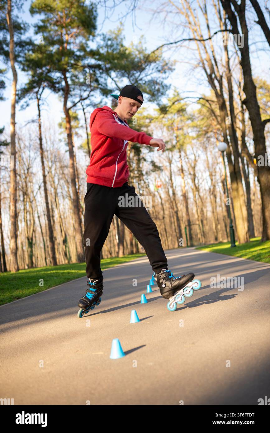 A skater rolling around blue cones on a path Stock Photo