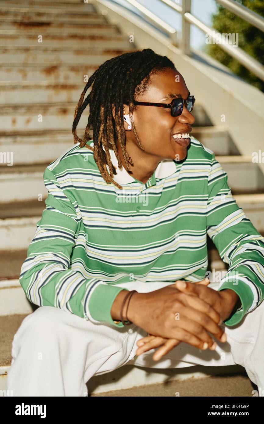 Happy Black Man with Dreadlocks Sitting on Stairs Outdoors Stock Photo