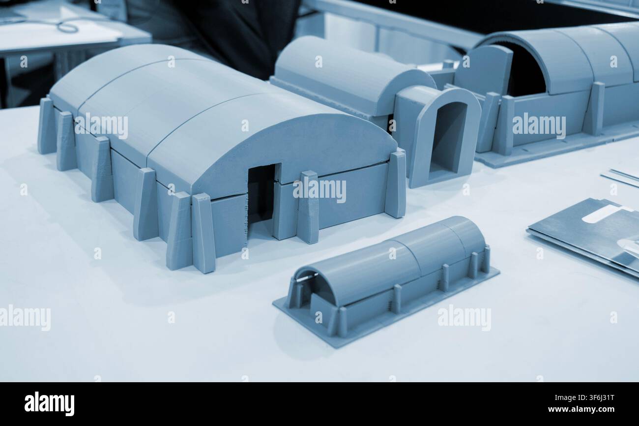 Prototype scale models of ground modular shelters printed on 3D printer from molten plastic. Ground-based defensive structures with arched roof and fortified entrances created 3D printer. 3D printing Stock Photo