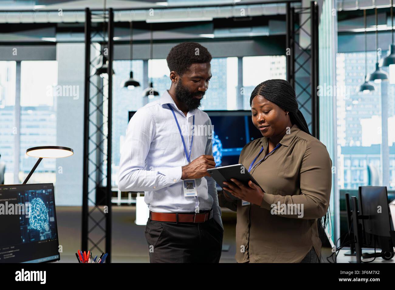 Teamworking engineers in office using AI on device to streamline app development. IT colleagues using tablet to run debugging applications with machine learning technology Stock Photo